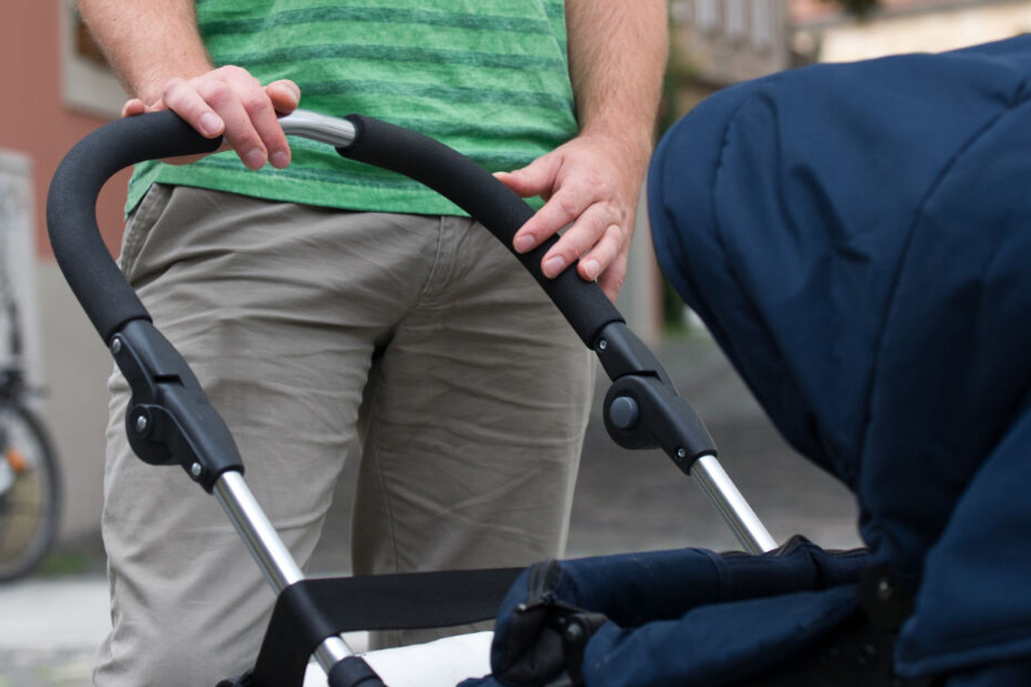 Ein Vater steht vor seinem Kinderwagen.