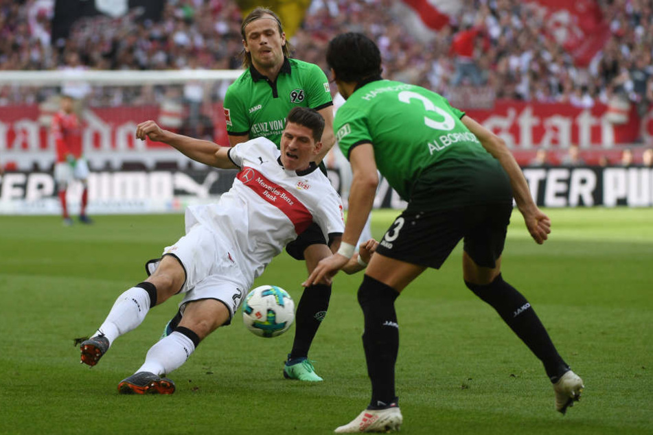 Stuttgarts Mario Gomez (m.) im Zweikampf mit Hannovers Iver Fossum (l.) und Miiko Albornoz.