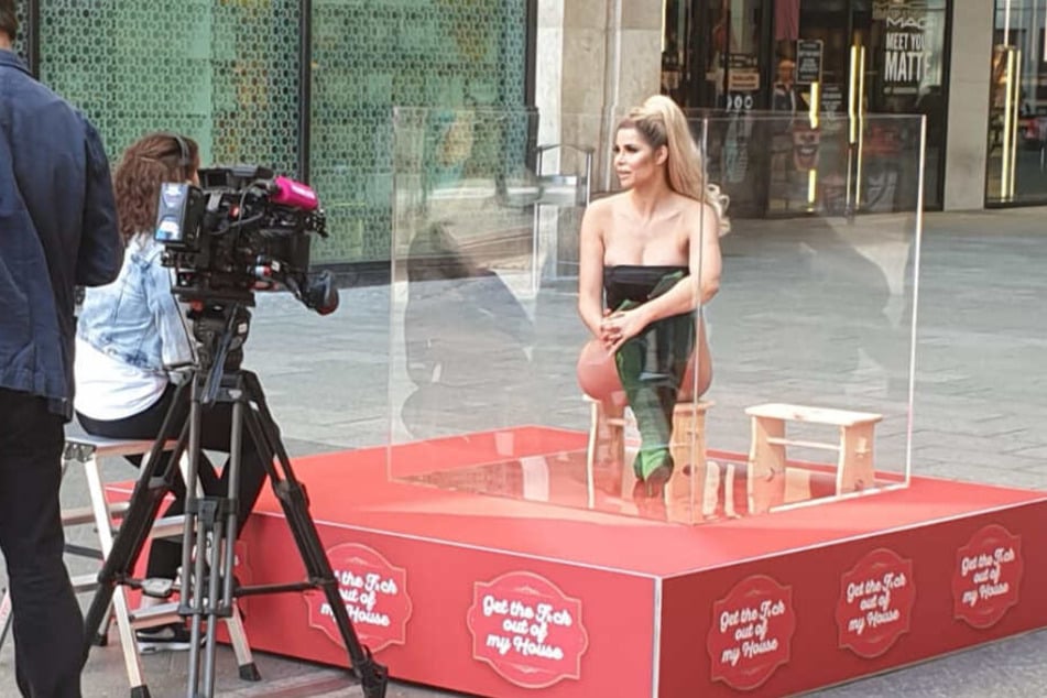 Micaela lässt sich im Glaskasten von einigen Journalisten interviewen.