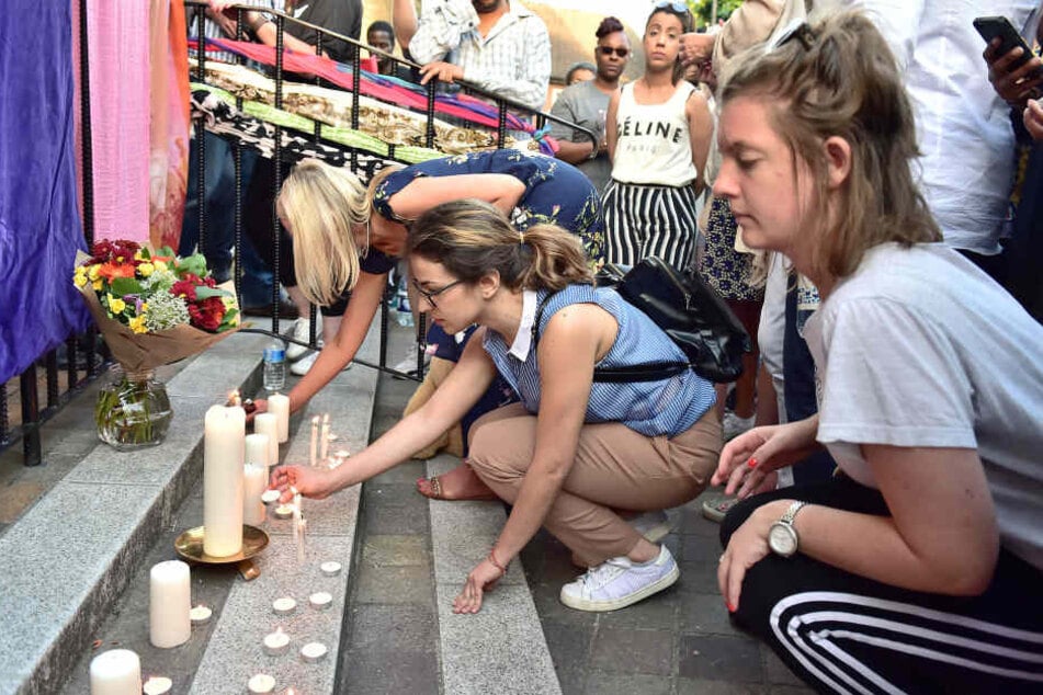 Menschen zünden im Stadtteil Notting Hill Kerzen an.