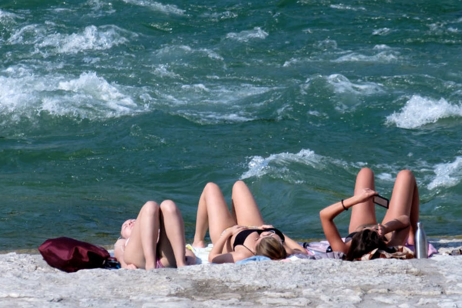 Frauen genießen bei hohen Temperaturen das Wetter an der Isar. (Symbolbild)