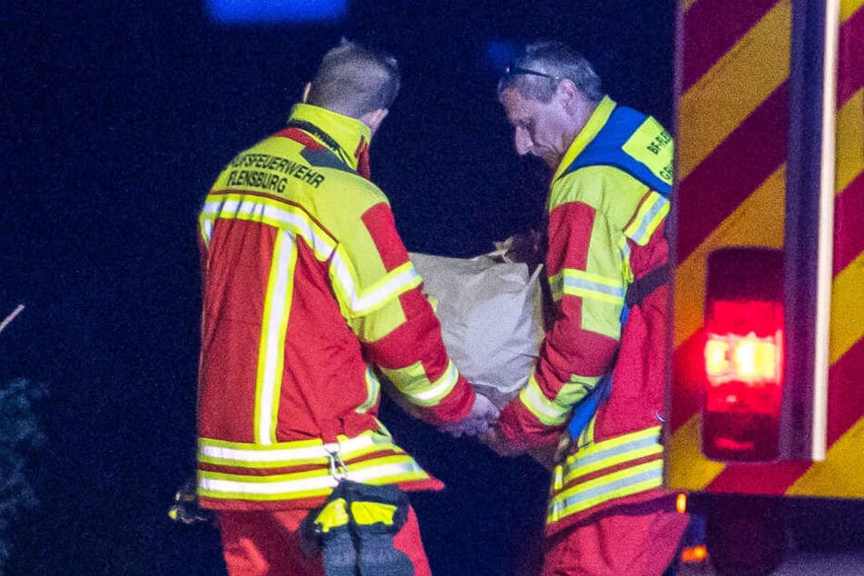 Zwei Feuerwehrleute tragen den Stein von der A7.