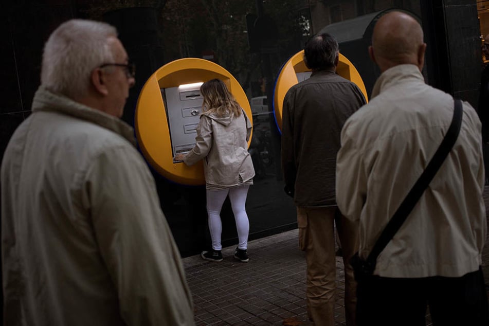 Bankkunden heben in Barcelona Bargeld von Geldautomaten ab.