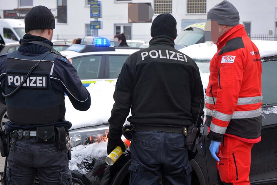 Polizei und Sanitäter stehen am Unfallfahrzeug.