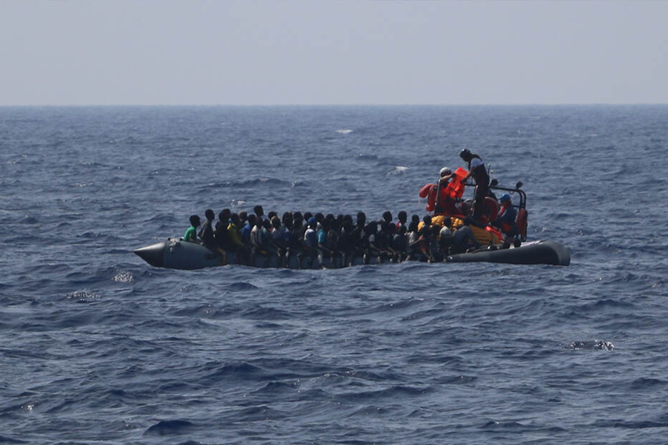 Ein Team der Hilfsorganisation SOS Mediterranee verteilt Rettungswesten auf einem in Not geratenen, im Mittelmeer treibenden Schlauchboot.
