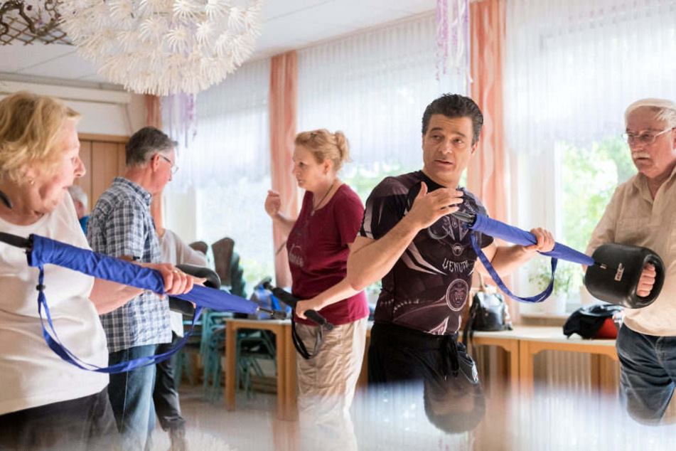 Kursleiter Luigi Pariser erklärt während eines Selbstverteidigungskurses für Senioren den Einsatz eines Regenschirms.