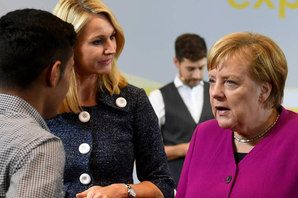 Merkel (r) begrüßt zusammen mit Ariane Reinhart (M), Continental-Personalvorstand, einen jungen Mann in der Zentrale des Continental-Konzerns.