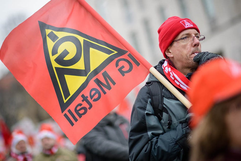 Mit IG Metall-Flaggen ziehen die Demonstranten auf die Straße.