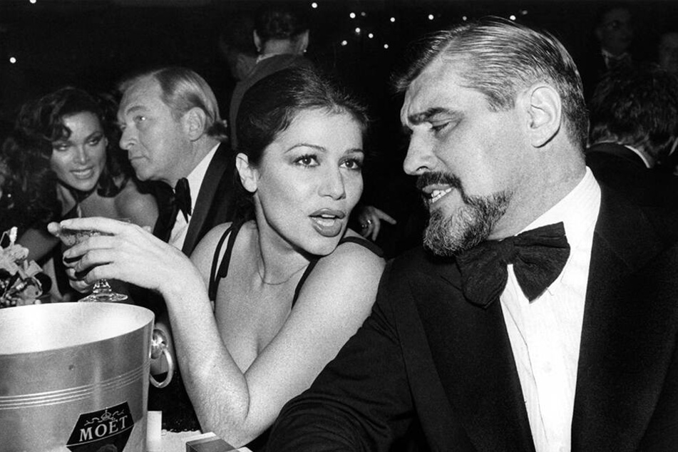 15.01.1977: Hannelore Elsner und der Schauspieler und Mario Adorf sitzen während des Deutschen Filmballs in München.