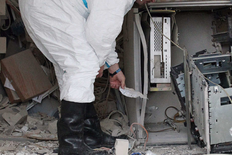 Ein Kriminaltechniker steht vor einem zerstörten Geldausgabeautomat. (Symbolbild)