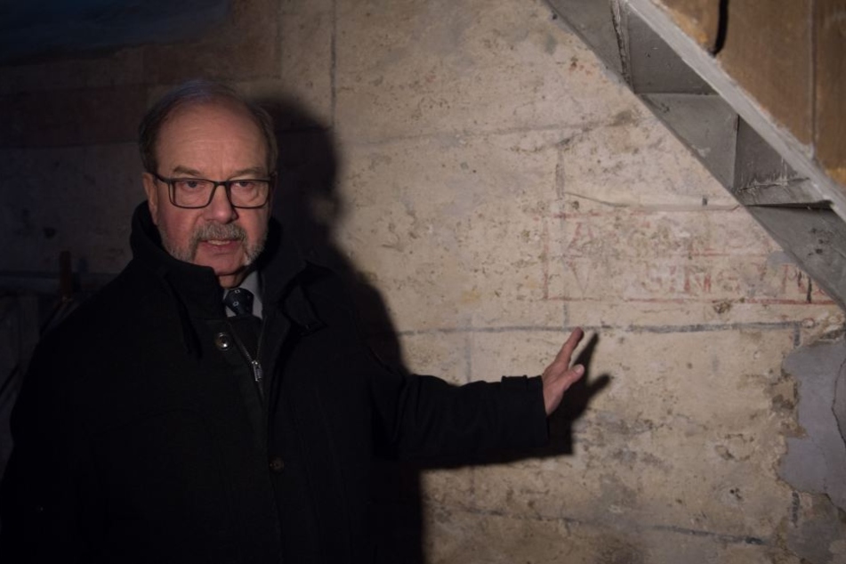 Kirchenvorstand Hans Beck zeigt die Schriften, die bisher durch Putz verdeckt waren.