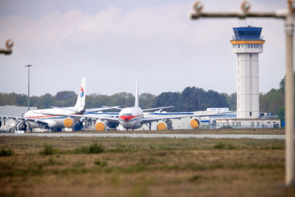 Zwei Airbus-Flugzeuge einer chinesischen Fluggesellschaft stehen auf einer Parkposition vor dem Tower des Airports. Seit Monaten tut sich dort kaum etwas.
