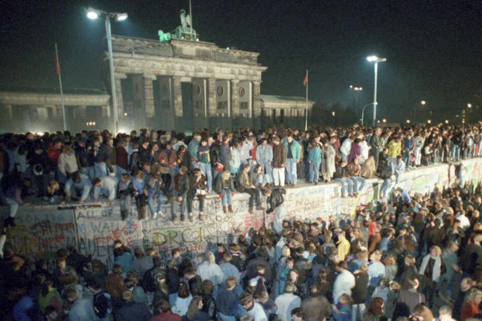 Berliner sitzen in der Nacht vom 09. auf dem 10.11 auf der Mauer vor dem Brandenburger Tor.