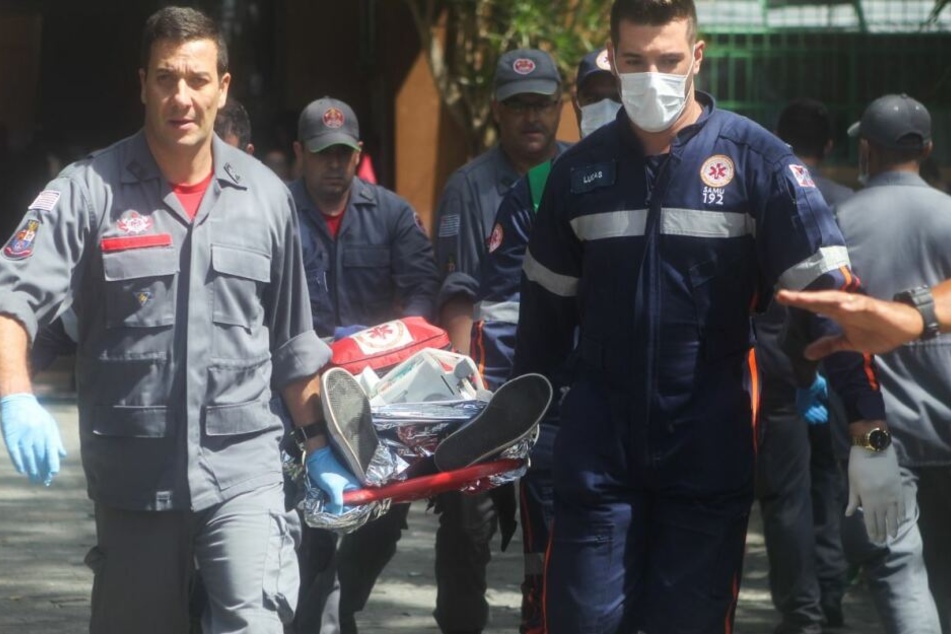 Einsatzkräfte tragen eine tote Person davon.