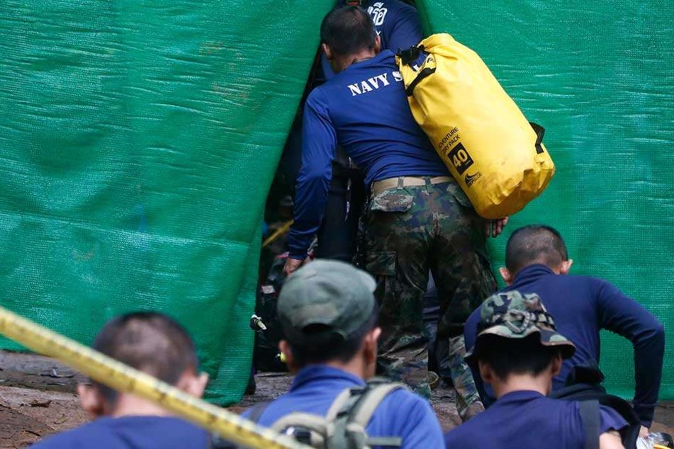 Rettungstaucher der Marine treffen mit Sauerstoff-Flaschen am abgesperrten Eingang zu der Höhle ein, in der zwölf Jungen einer Fußballmannschaft und ihr Trainer seit 23. Juni eingeschlossen sind.