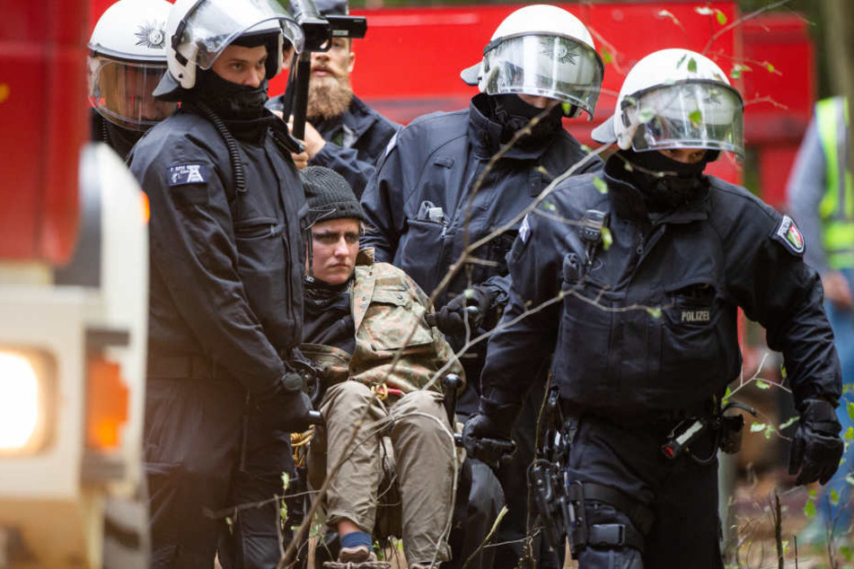 Polizisten nehmen eine Aktivistin in Gewahrsam.