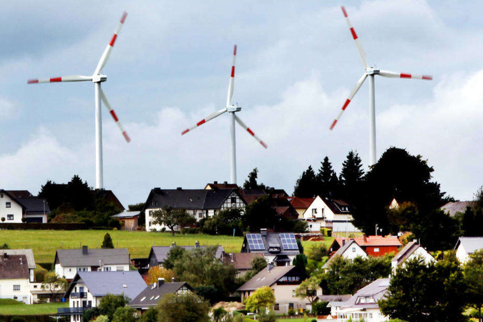 Windräder des Windparks Schöneseiffen in Gemünd drehen sich hinter Wohnhäusern.
