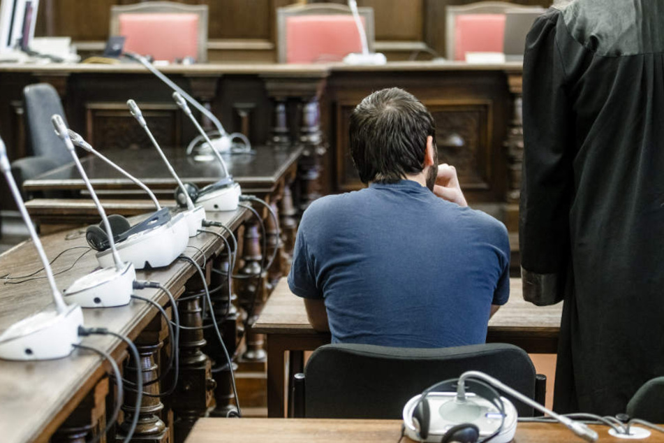 Der Angeklagte sitzt in einem Sitzungssaal des Strafjustizgebäudes.