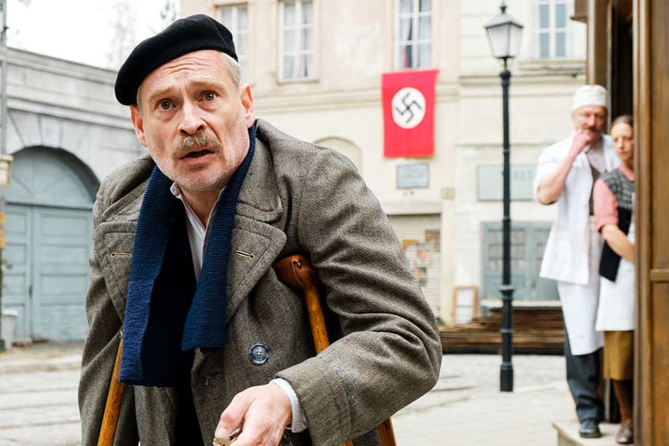 Trafikant Otto Trsnjek (Johnannes Krisch) schaut fassungslos zu seinem Laden, der mit abstoßenden Schmierereien verwüstet wurde. Herr und Frau Metzger lachen sich vor der Hakenkreuzfahne ins Fäustchen.
