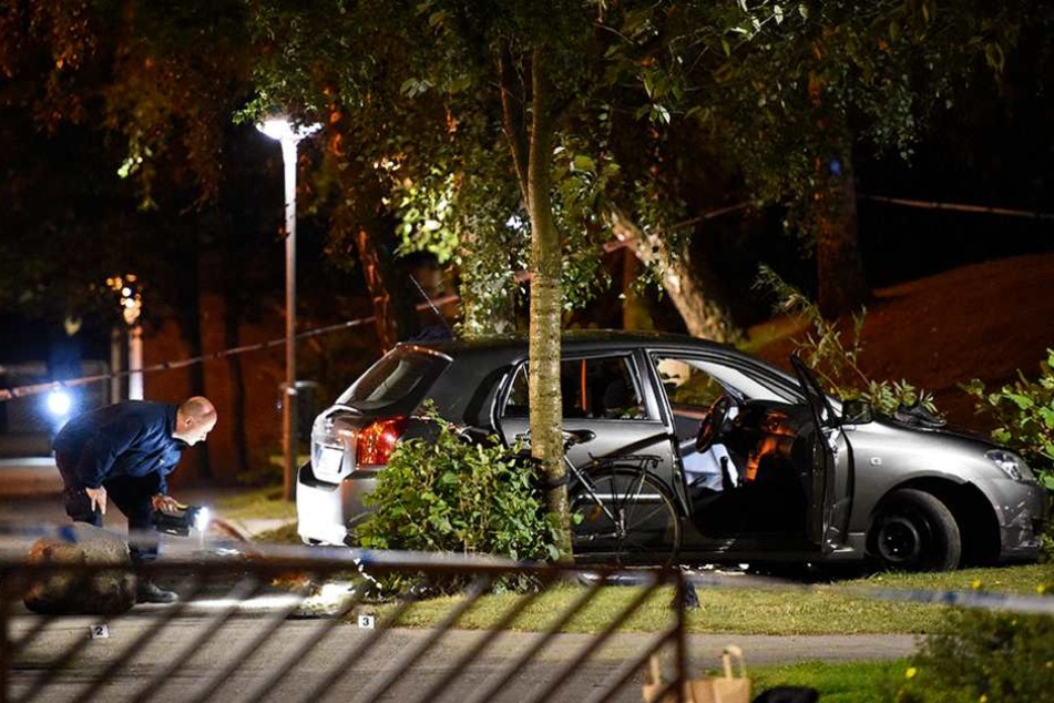 Polizisten untersuchen das beschossene Auto.