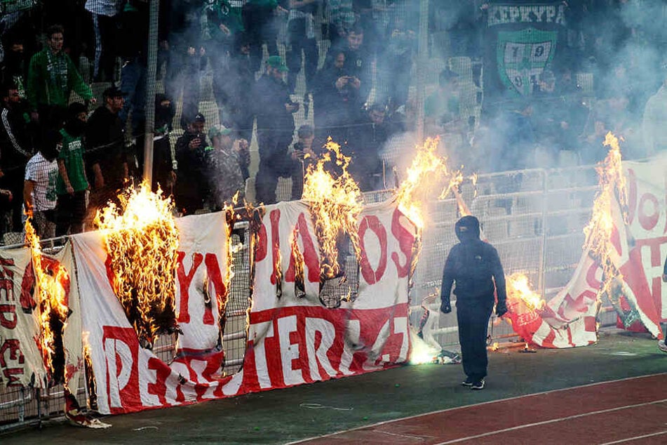 Vermummte Panathinaikos-Randalierer verbrennen ein Banner von Olympiakos Piräus.