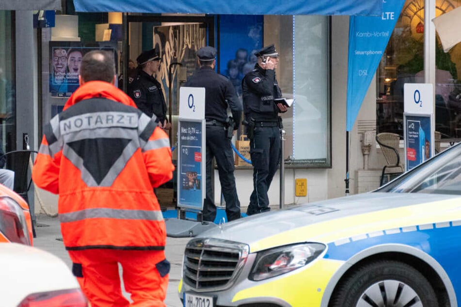 Die Polizei steht vor dem überfallenen Handy-Geschäft.