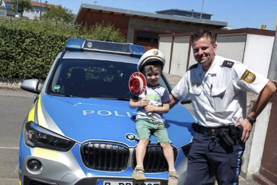 Die Polizisten haben ihr Versprechen eingelöst und sind mit dem Streifenwagen beim kleinen Jakob (l.) vorbeigefahren.