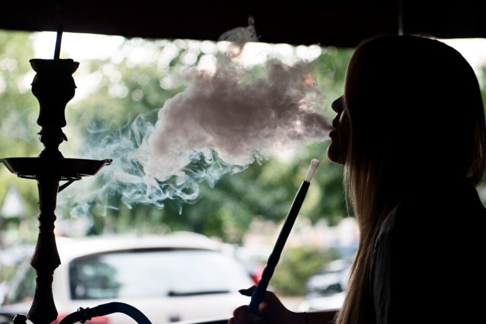Eine junge Frau raucht eine Shisha in einem Rauchercafé.