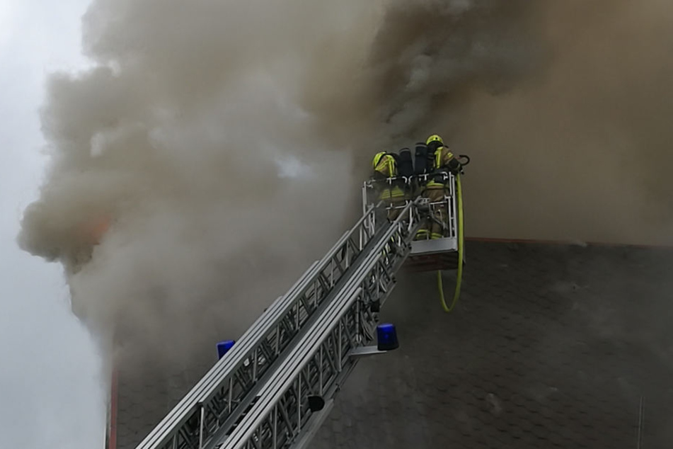 Einsatzkräfte bekämpfen die Flammen aus dem Korb einer Drehleiter.
