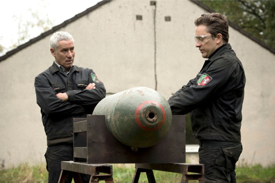 Maiwald (Ralph Herforth,, li.), der Leiter der Dienststelle des Kampfmittel-Räumdienstes, und sein Sohn und Kollege Joachim (Adrian Topol) üben mit einer Bomben-Attrappe.