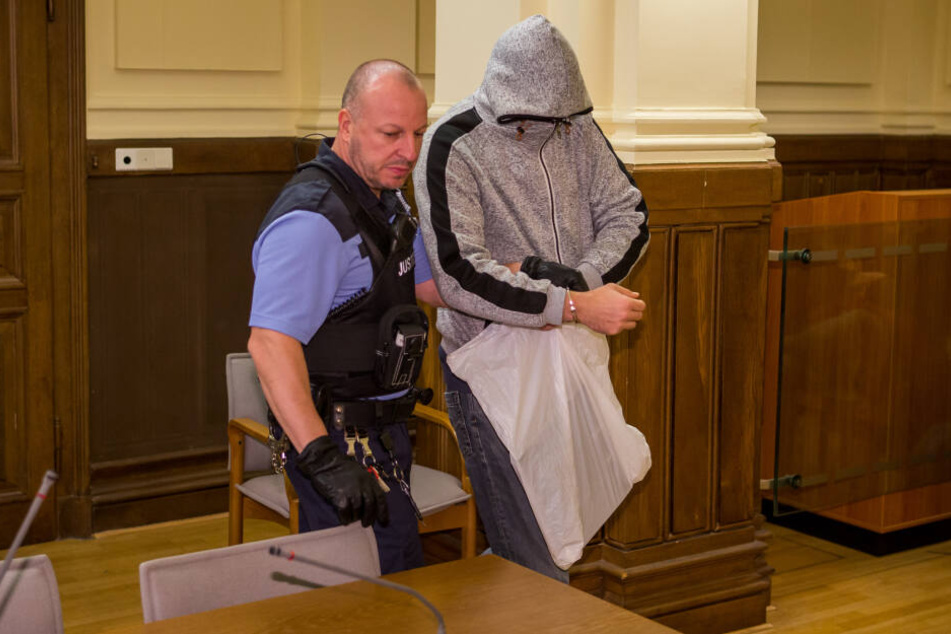 Mit tief ins Gesicht gezogener Kapuze lässt sich Kinderschänder Robert G. (39) von einem Justizbeamten in den Gerichtssaal führen.