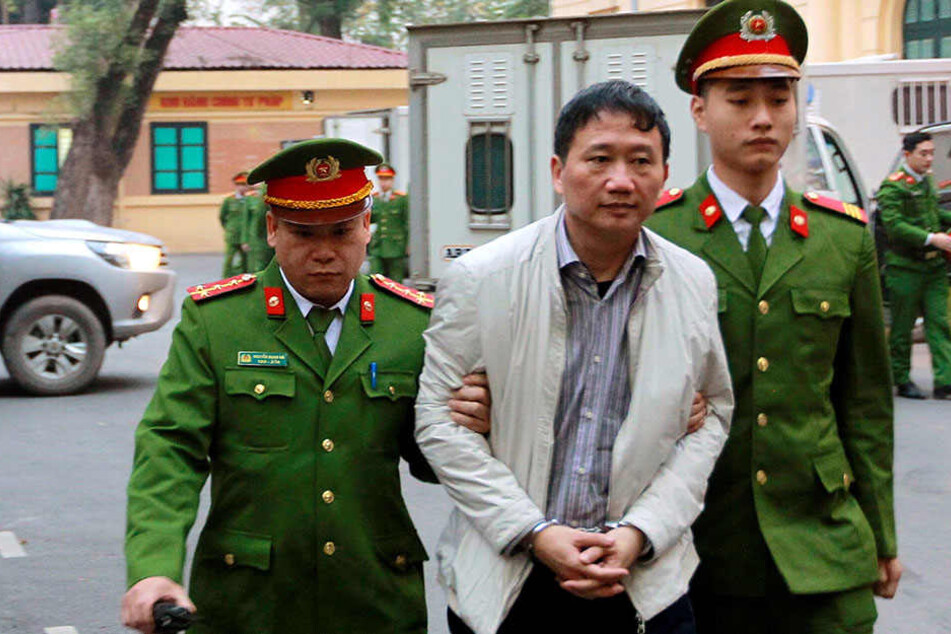 Der angeklagte Geschäftsmann Trinh Xuan Thanh (M) wird von Polizisten zu, einem Gericht in Hanoi (Vietnam) gebracht.