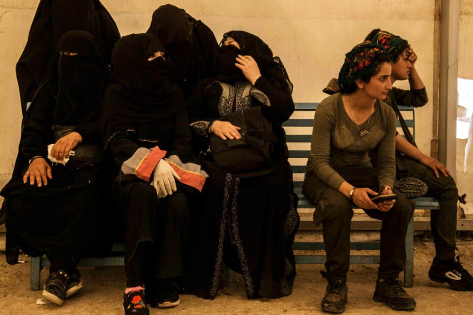 Frauen (l), die mit Kämpfern der Terrormiliz Islamischer Staat (IS) verwandt sind, sitzen im Juni neben ihren Wächterinnen.