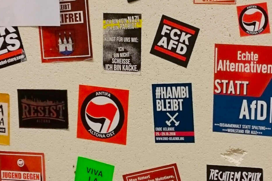 Auf einer Stellwand sind Aufkleber unter anderem von der Antifa Altona Ost und mit AfD-feindlichen Sprüchen angebracht.