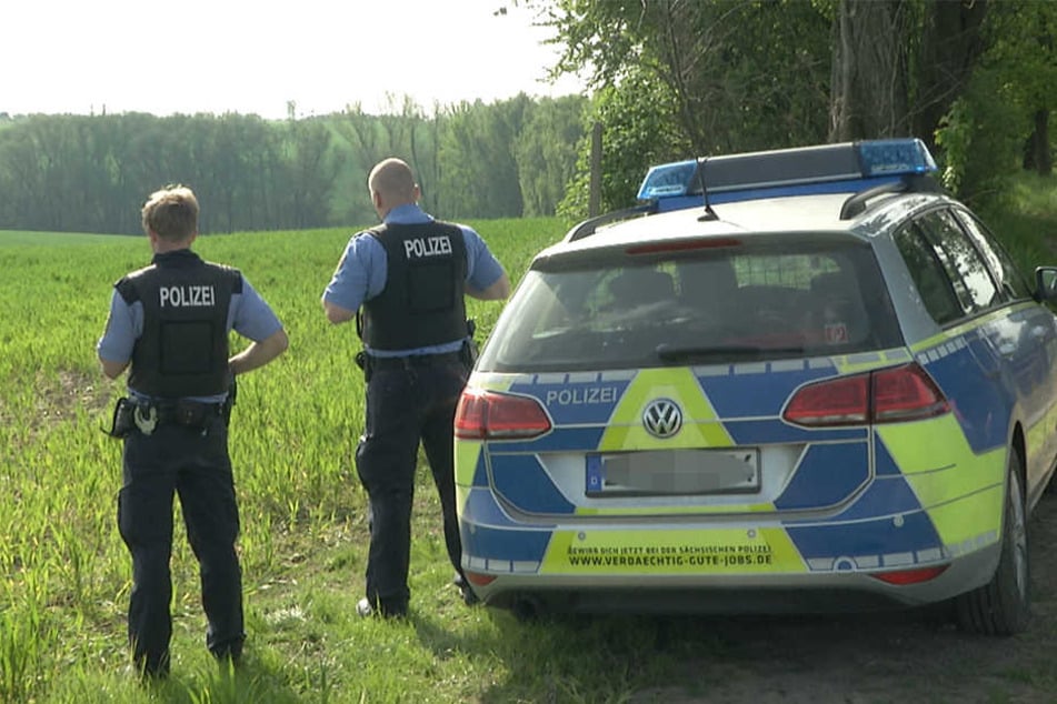 Polizisten sichern die Zufahrt zum Waldstück, in dem der tote Jäger und der Rehbock gefunden wurden.