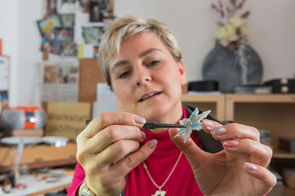 Die gelernte Porzellan-Malerin setzt einen funkelnden Kristall auf einen ihrer zarten Schmuck-Sterne.