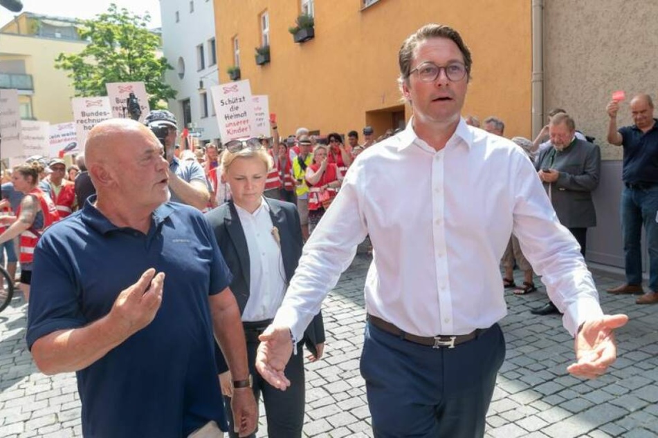 Andreas Scheuer (CSU) unterhält sich mit demonstrierenden Anwohnern. Sie sind gegen den Bau einer neuen Trasse für den Nordzulauf im bayerischen Inntal.