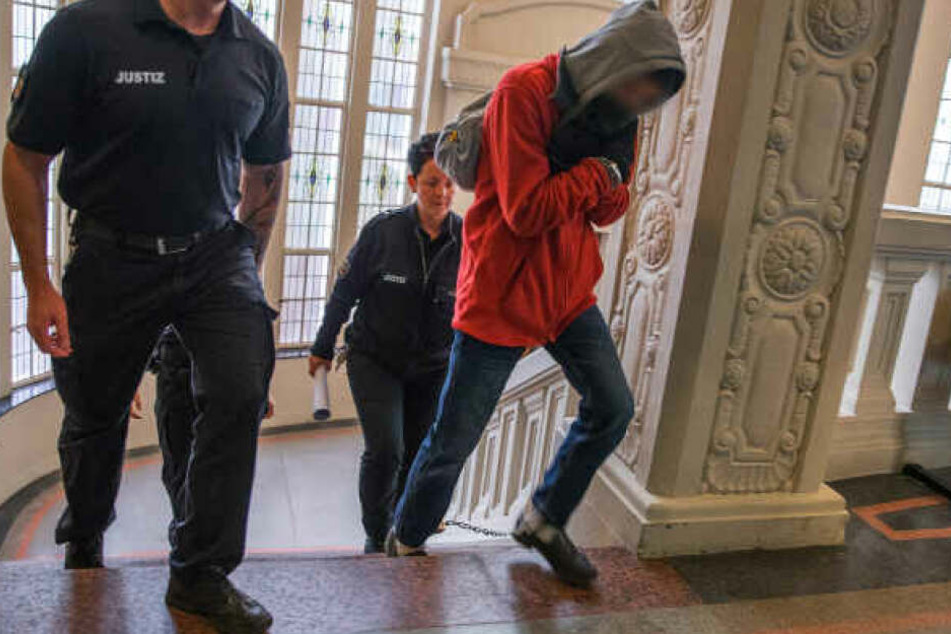 Der Angeklagte wird zum Prozessbeginn um den Mord an einem Rentner in Wittenburg zum Gerichtssaal geführt.