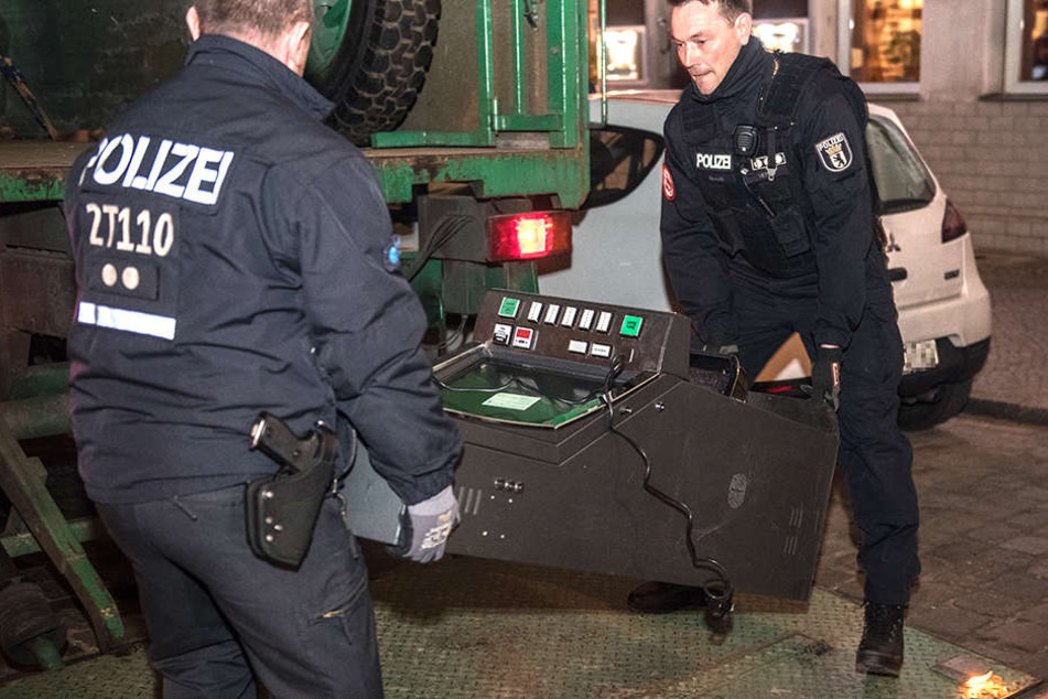 Zwei Polizisten beschlagnahmen einen Glücksspielautomaten.