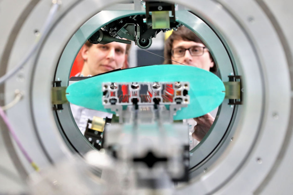 Die Entwickler Rainer Wallasch (l) und Ramon Tirschmann bereiten einen Versuch auf ihrer Pilotanlage mit Orbitalwickeltechnologie an der TU Chemnitz vor.