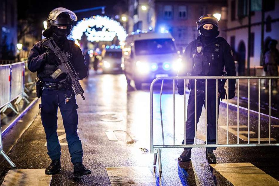 Schwer bewaffnet Polizisten stehen am abgesperrten Weihnachtsmarkt von Straßburg.