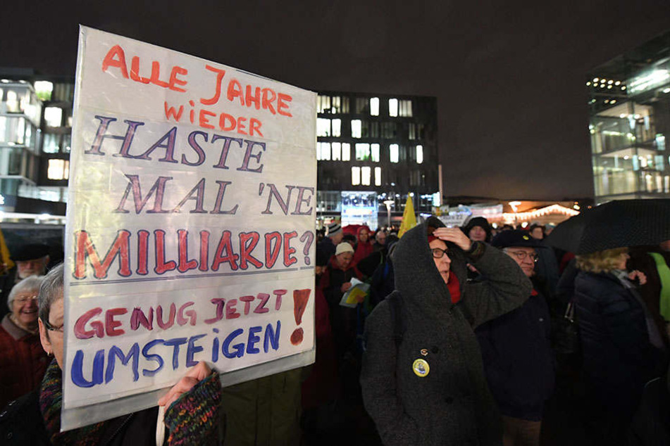 Eine Teilnehmerin der Montagsdemo hält ein Plakat mit der Aufschrift "Alle Jahre wieder - Haste mal 'ne Milliarde? Genug jetzt umsteigen!" in den Händen.