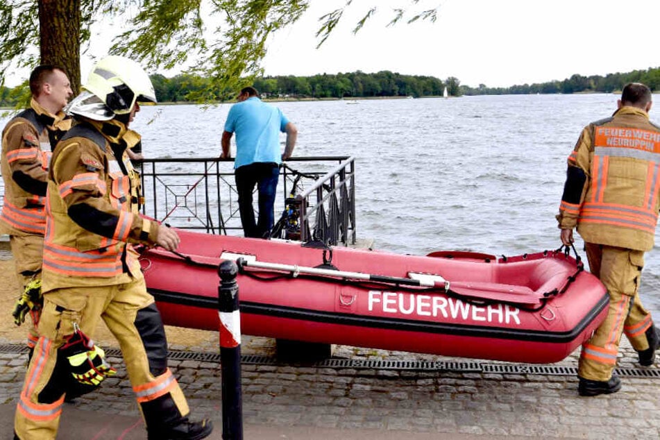 Einsatzkräfte der Feuerwehr tragen ein Schlauchboot in das Wasser.