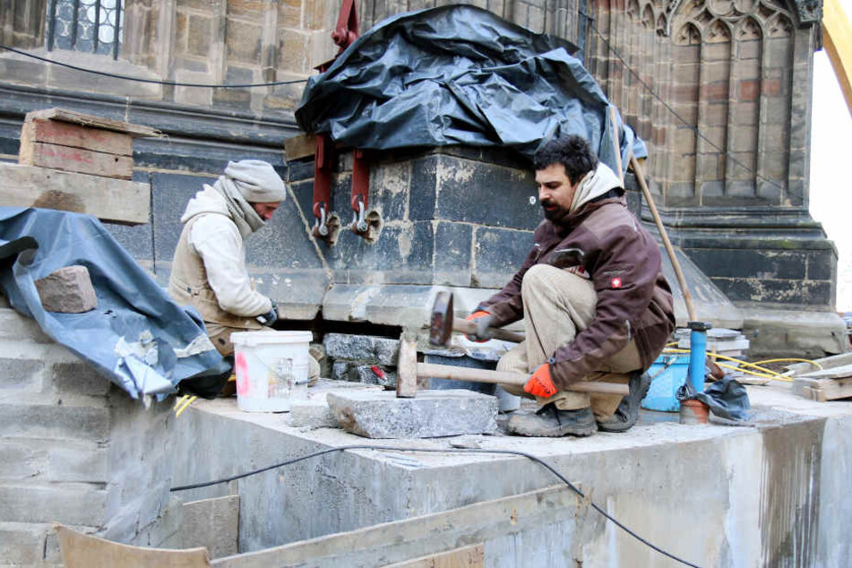 Die Steinmetzmeister Matthias Mehlhorn (l) und Sebastian Steinert sanieren ein altes Fundament am Dom in Zwickau, damit der Pfeiler an der Ostseite der Kirche wieder tragfähig wird.