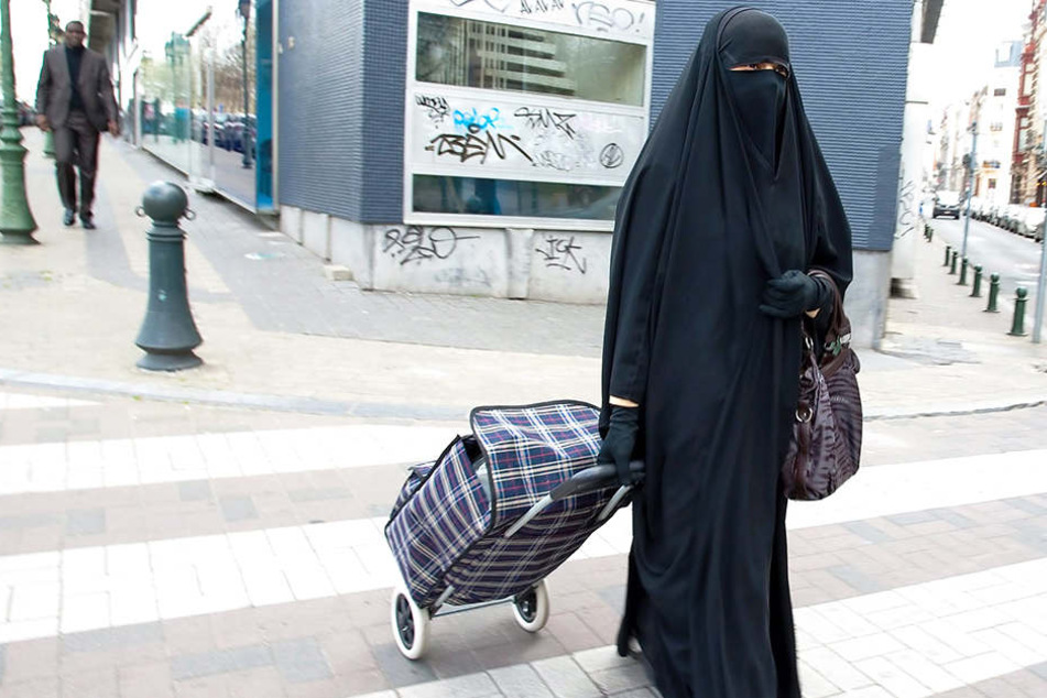 Mit einem Niqab bekleidet läuft eine Frau durch die Straßen.