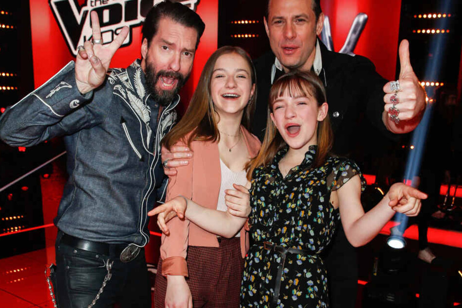 Die Schwestern Mimi (l.) und Josefin freuen sich mit Coach Alec Völkel (l.) Sascha Vollmer (r.) von BossHoss beim Finale von "The Voice Kids".