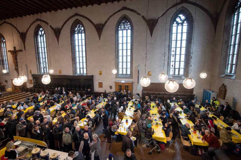 Besucher sitzen am Sonntag in der Vesperkirche an Tischen.