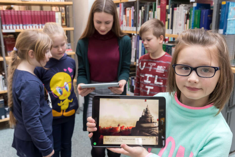 Delia Anton-Ronczka (19) zeigt Nika (v.), Anna-Bella, Lina und Tobias (alle 8), wie die neue App "Die große Wörterfabrik" funktioniert.