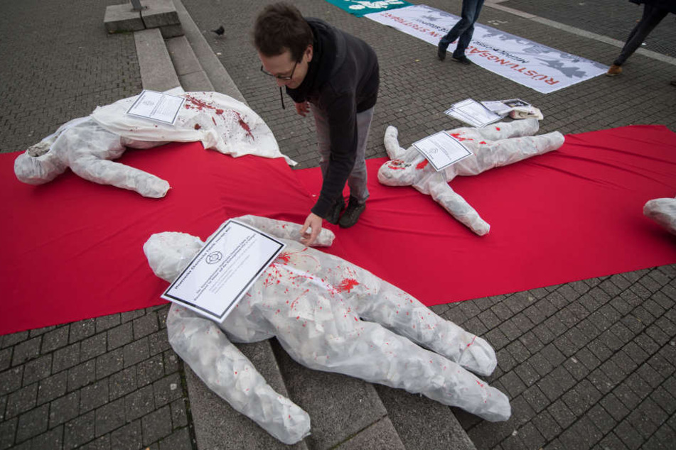 Ein Rüstungsgegner legt vor dem Rathaus bei einer Kundgebung von Rüstungsgegnern gegen die Militärmesse ITEC ein Plakat auf ein symbolisches Kriegsopfer.