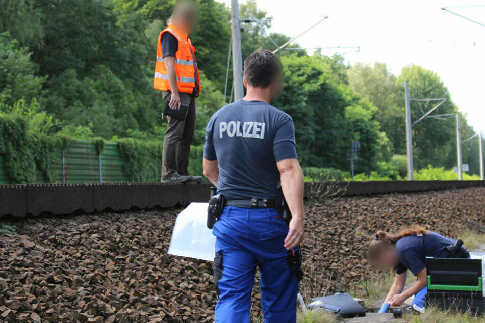 Mitarbeiter der Bahn und der Kriminalpolizei untersuchen am Samstag am Gleisbett einen Kabelschacht an der Bahnstrecke in der Nähe von Groß Behnitz bei Berlin.